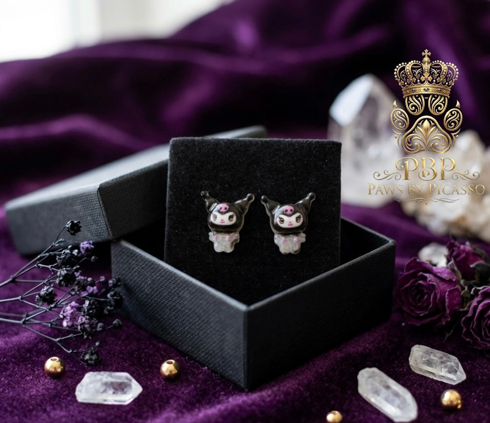 Pair of earrings in a black box on a purple fabric background 