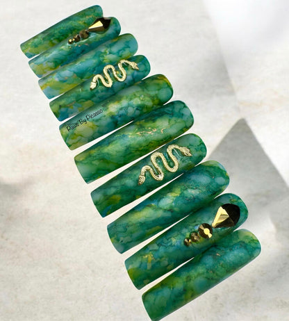 Set of green marbled hair ties with gold accents on a light background
