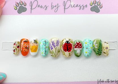 Decorative nail art clips with various designs on a white background, branded 'Paws by Picasso'.
