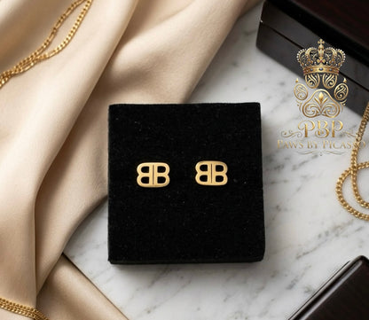 Gold earrings on a black display with 'Paws by Picasso logo in the corner.