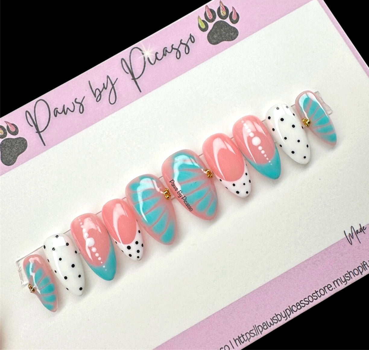 Set of decorative false nails with pink, turquoise, and white design on a 'Paws by Picasso' branded card.