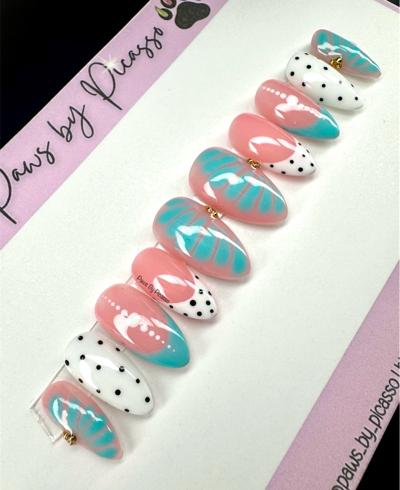 Set of decorative false nails with pink, turquoise, and white designs on a branded card.