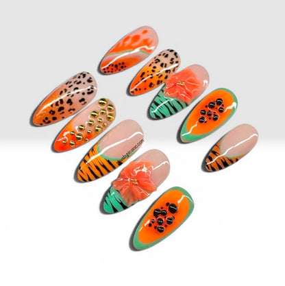 Ten almond-shaped press-on nails with vibrant tropical and animal-inspired designs, including orange and black stripes, leopard print, green and orange patterns, and a 3D orange flower accent, displayed on a light gray background.